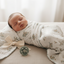 Newborn baby swaddled in a floral blanket with a bow and pacifier on a light surface.