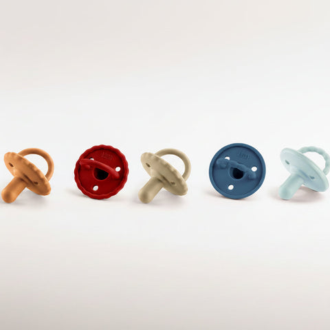 Row of colorful baby pacifiers on a white background